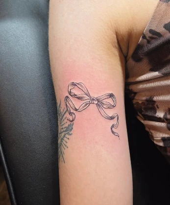 Small fine-line bow and flower tattoo