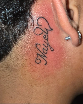 Small lettering tattoo near the ear